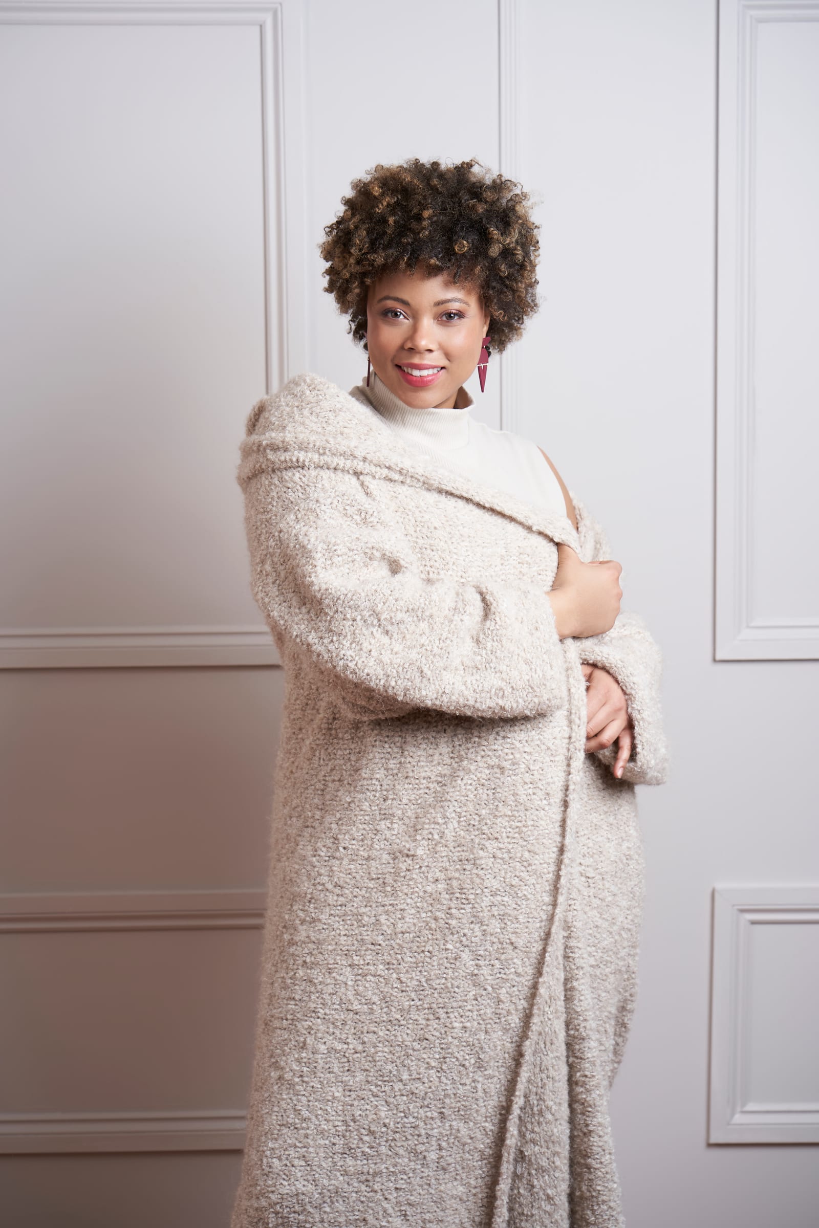 Ms Curvaceous model Danielle Nash in a cream knit coat against a white panelled door, from her MODE at Rowan shoot.
