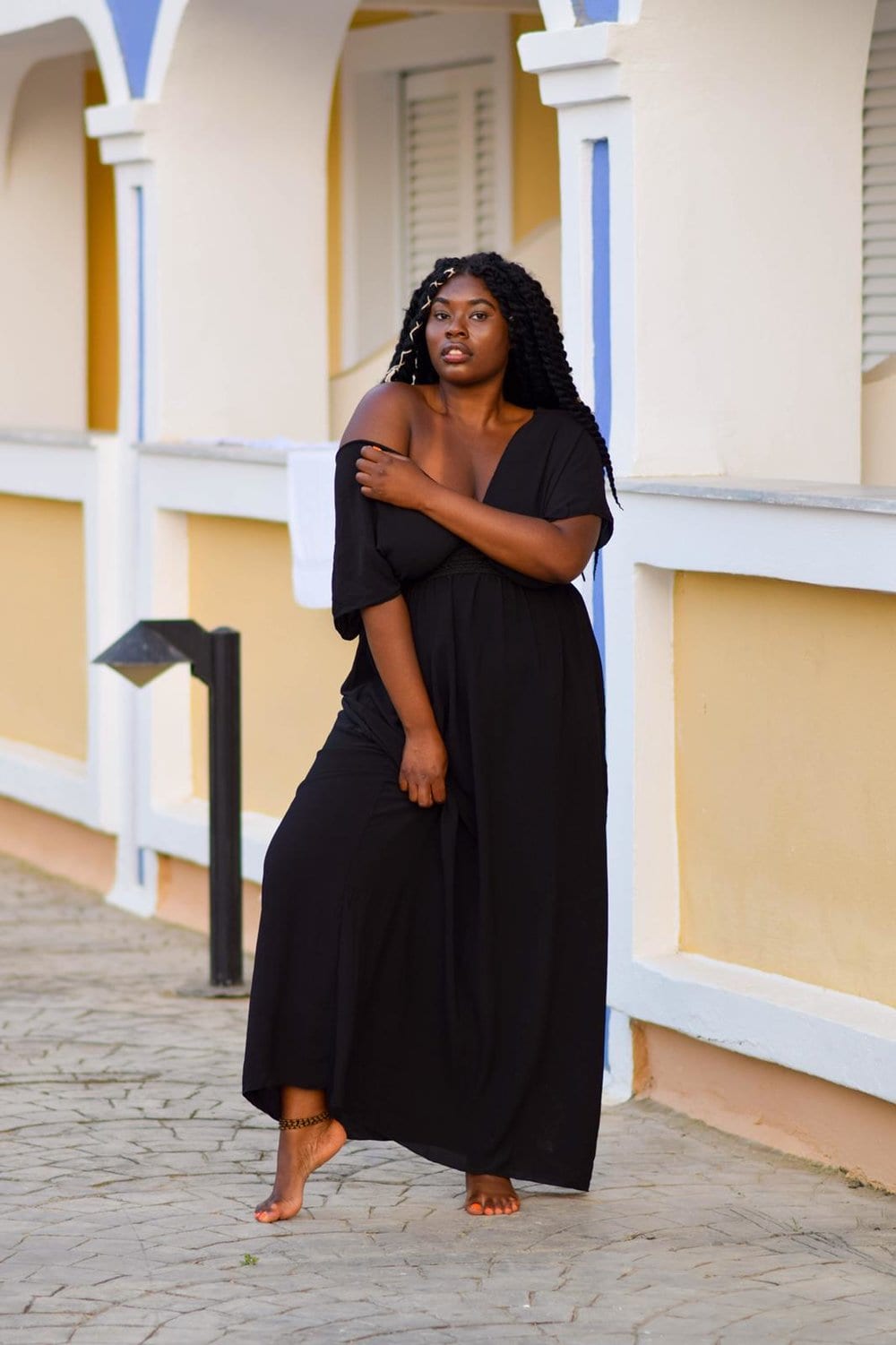 Ms Curvaceous model Corrine standing in a black maxi dress in front of a colonial building.